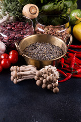 Still life vegan food set on dark background. Concept healthy eating. Beans, lentils, chili, nut, cucumber, spinach, mushrooms shimidzhi, cherry tomato.