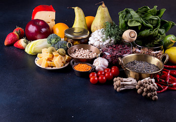 Still life food set on dark background. Concept healthy eating. Broccoli, chicory, beans, lentils, chili, nut, cheese, garlic, spinach, mushrooms shimidzhi, cherry tomato.