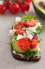 An avocado sandwich with tomatoes and cheeses. serving on the table	