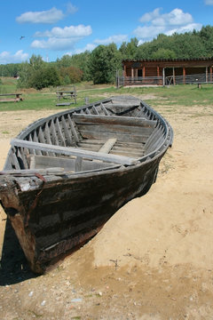 Old wooden malfunctioning boat in the sand. Summer sunny rural landscape