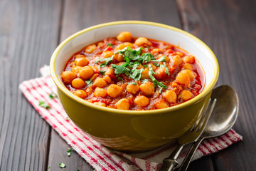 Spicy Chickpea curry Chana Masala in bowl on dark wooden table. Traditional Indian dish. Selective focus.