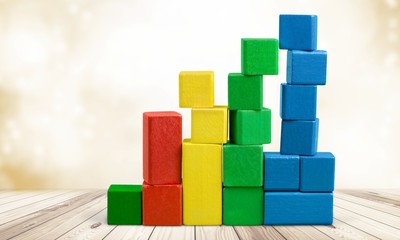 Obraz premium Hand with toy wooden blocks stack, towers of blank multicolor box cubes over white background