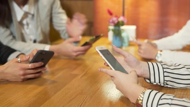 Close-up of girls' hands typing messages on smartphones.