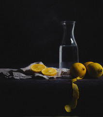 Still life with lemons, water and linen against a dark background © Andrea
