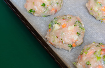 Raw chicken meatballs with vegetables - preparation for baked in the oven. Ingredients on the counter Healthy protein cutlets, minced cutlets. Proper, healthy food concept. Copy space