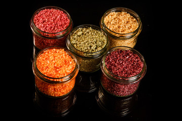 top view of five glass jars filled with different colors sea salt