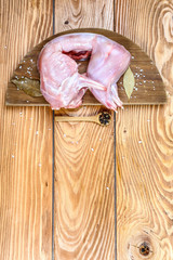 Raw whole rabbit with spices on a dark rustic background. Top view