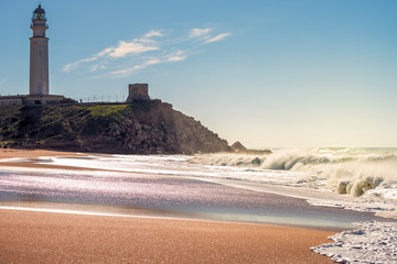 Lighthouse on hill next to the shore of the beach