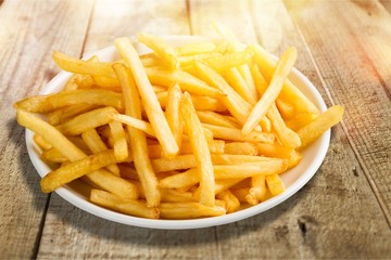 Plate of french fries on wooden table