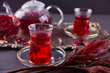 Cups of hot red karkade tea with teapot on the tray