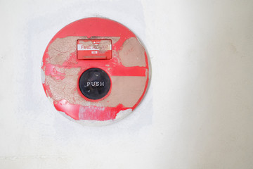 The old red fire alarm button on the cement wall