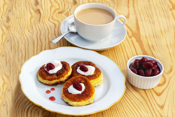 morning coffee with milk and cottage cheese pancakes with sour cream and cherry jam