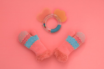 Children's rattle and mittens on the corral background, large palm, monochrome, minimal style, art