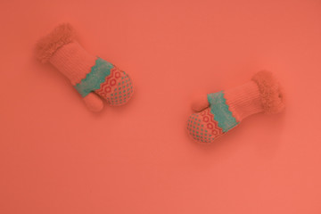 Children's mittens with a turquoise stripe on the coral background, art, minimal, close-up, copyspase