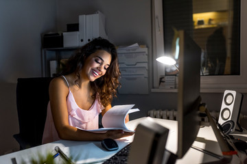 Happy young woman sitting in office and working