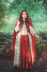 Beautiful woman in medieval dress and red cloak