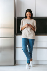 Happy young woman standing at the kitchen