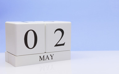 May 02st. Day 2 of month, daily calendar on white table with reflection, with light blue background. Spring time, empty space for text