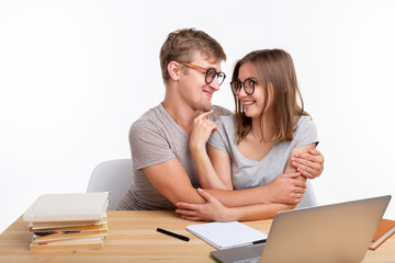 People and education concept - Two fallen in love funny students sitting at the wooden table with...
