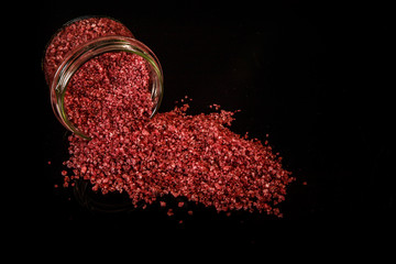 top view big red organic sea salt poured out from small glass jar