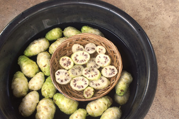 Noni slice basket and noni fruit in water in black basin