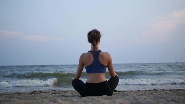 Girl doing yoga pose on the beach. Static. Sea or ocean happy woman relaxing. Water and waves. Hands and blue sky. Exercise calm and harmony. Hair and wind.