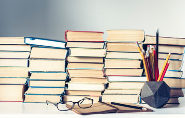 Notebook, pencils, glasses and stack of books, school background for education learning concept.