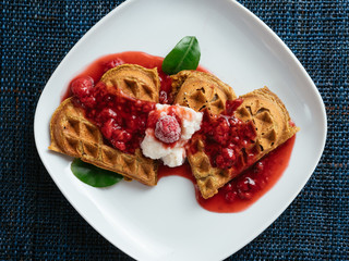 Heart shaped vegan beet waffles with a raspberry sauce. 
