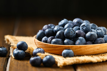 Fresh blueberries in wooden plate on a wooden table