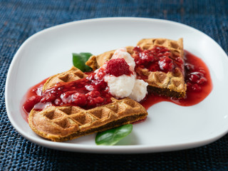 Heart shaped vegan beet waffles with a raspberry sauce. 