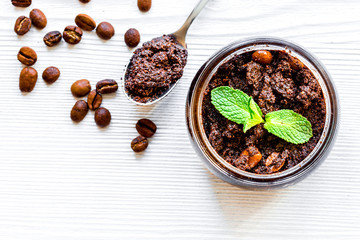 Homemade cosmetics with coffee scrub on white desk background top view