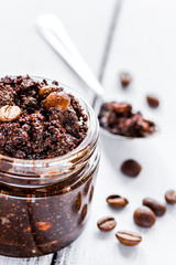 Homemade cosmetics with scrub and coffee beans on desk background