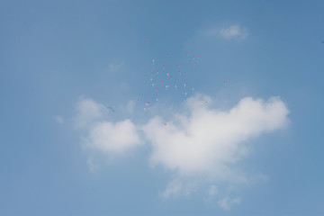 white and red ballons far away in the blue sky
