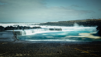 FEBRUARY/02/2019 Waves jumping on dock of the fishing cove of La Santa in Lanzarote during a storm, long exposure photography