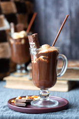 Hot chocolate in a mug and books on a dark background.