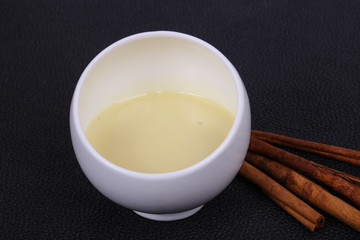 Condenced milk in the bowl with sinnamon and pastry