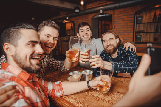 Long-awaited meeting of friends men. They drink beer in bar, take selfies