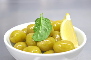 Whole green Greek olives in a white bowl. close up. vertical view of olives.