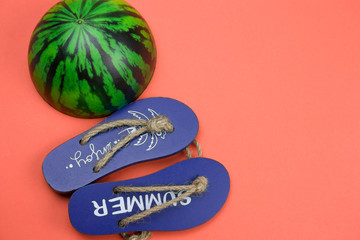 decorative wooden flip flops and squishy toy watermelon  on a coral background copy space