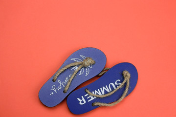 decorative wooden flip flops on a coral background copy space
