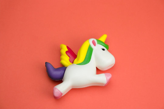 top view squishy unicorn toy on a coral background