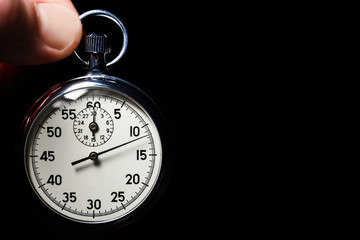 Male hand hold the analog stopwatch on a black background, close-up, isolate, copy space