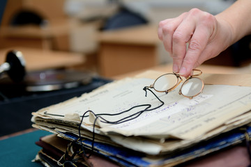 female fingers hold pince-nez over old papers