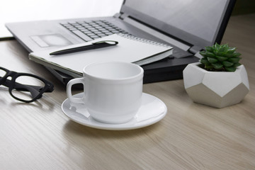 workplace with  laptop, notebook, glasses and a mug of coffee selective focus
