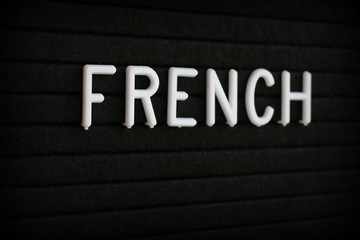 The word French in white plastic letters on a black notice board 