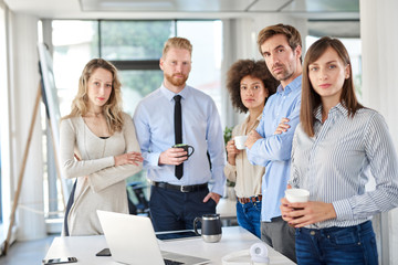 Small group of business people standing and posing at office. Start up business concept. Multi ethnic goroup.
