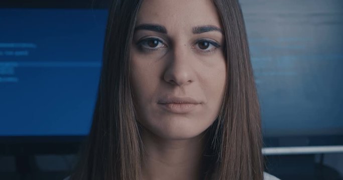 Young Woman Developer Programmer looking at camera at binary code background