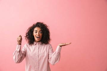 Happy beautiful young african woman posing isolated over pink wall background.