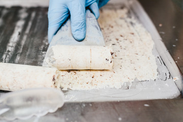 Rolling a white ice cream to prepare a cup of chocolate-wrapped ice cream