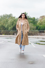 Beautiful woman in the beige coat talks by the phone on the street